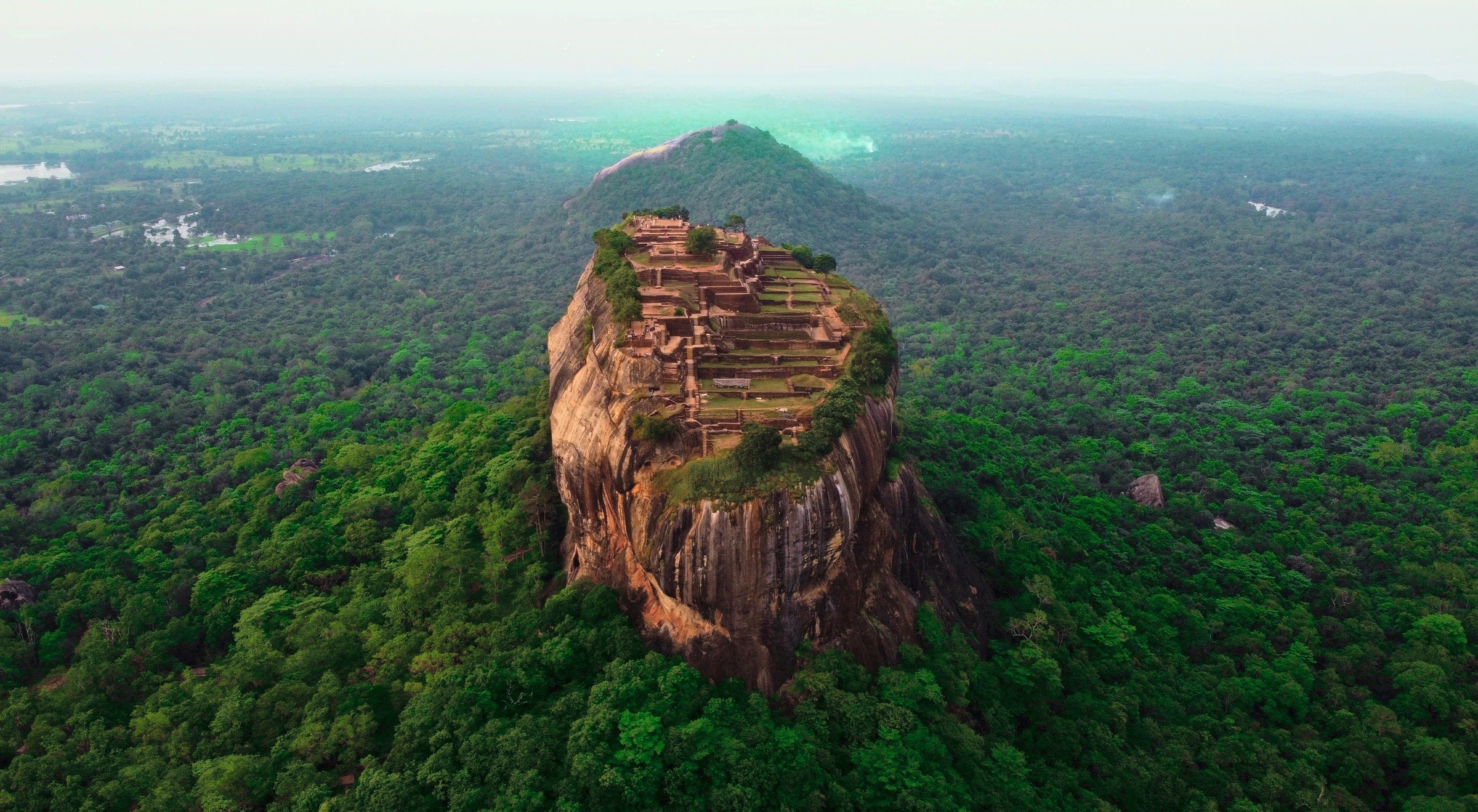 Aerial view of Sigiriya Rock Fortress and its summit ruins above the jungle canopy, Sri Lanka
